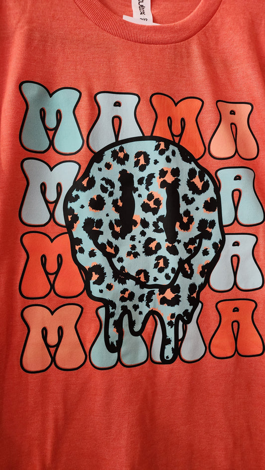 Orange tee with image of a smily face melting. The word mama is written 4 times behind the smiley face. Smiley is blue with leopards spots in orange. Mama is multi colored in orange and blues.